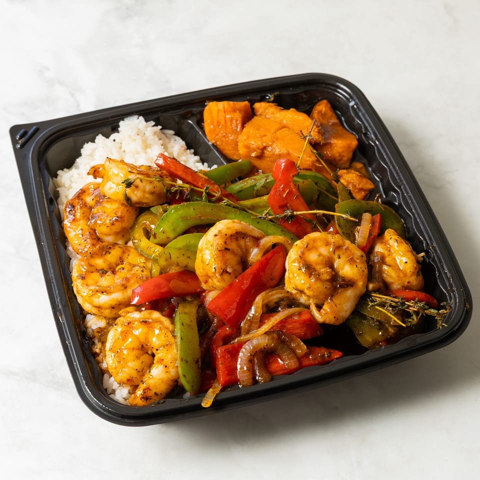 Takeout tray filled with seasoned shrimp, white rice, sautéed red and green peppers, onions, and roasted sweet potatoes.